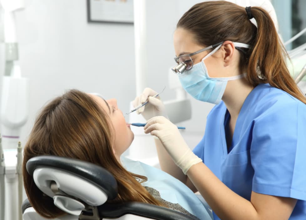 Dental professional performing a gentle teeth cleaning and exam for a patient in a modern dental office.