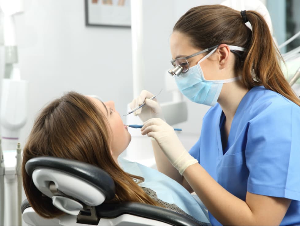 Dental professional performing a gentle teeth cleaning and exam for a patient in a modern dental office.