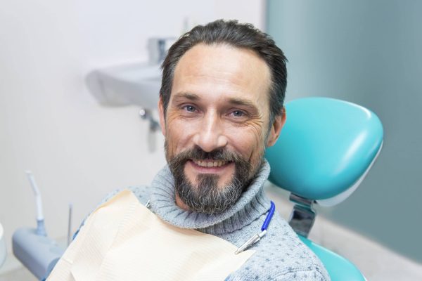 Smiling man in dental chair. Person at the dentist. Trust your smile to professionals.